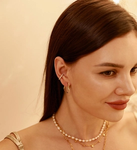 Close-up of elegant gold heart earring and shimmering diamond-encrusted ear cuff on model