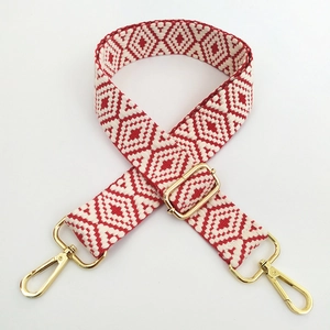 Detail of adjustable red and white geometric jacquard bag strap with gold metal hardware