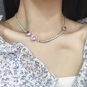 Pink heart tennis necklace with cubic zirconia gemstones worn on a female neck