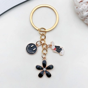 Detail of golden keychain with black smile, flower charms and white rabbit pendant