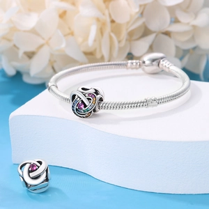 Detailed shot of a silver beaded charm bracelet with colorful zircon stones on blue backdrop