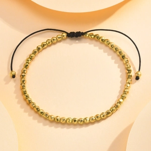 Detailed view of faceted gold beads with adjustable black braided string closure