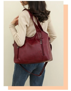 Detail view of burgundy PU leather shoulder bag with silver hardware and zipper pockets