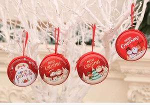 Close-up of four red round Christmas coin purses with festive patterns hanging on a branch