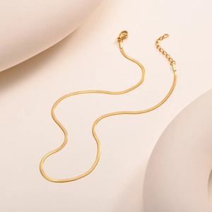Close-up of golden flat snake chain bracelet with sturdy lobster clasp and extension