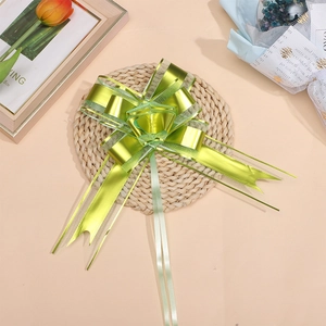 Golden green metallic organza pull bow placed on a woven mat for gift decoration