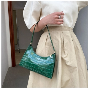 Detail of dark green crocodile pattern faux leather underarm bag with gold metal zipper