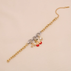 Detail of a gold stainless steel chain bracelet with cherry pendant and pear-shaped zircon