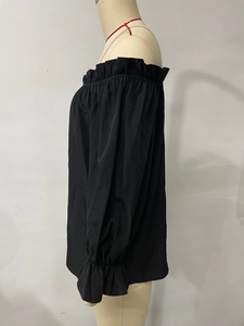 Détail d'un haut en mousseline noire à épaules dénudées avec un col à volants élégant