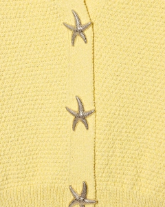 Détail d'un tricot jaune vif avec des boutons en métal argenté en forme d'étoile de mer