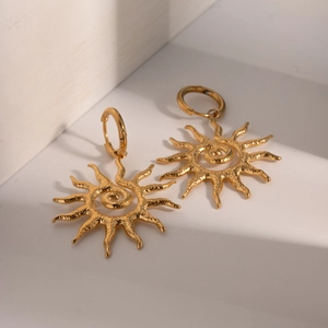 Macro shot of 18k gold stainless steel earrings with spiral sun motif and hammered texture