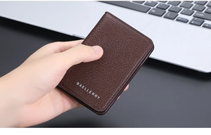 Close-up of a slim brown leather wallet with lychee texture held in a hand