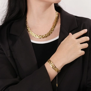 Golden woven snake chain necklace and bracelet set shown on a model with black blazer