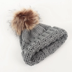 Winter knitted baby beanie in grey with large brown faux fur pom-pom for infant warmth