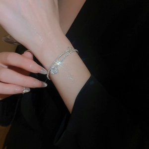 Close-up of sparkling heart pendant and double-layer silver chain on wrist
