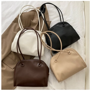 Close-up of minimalist leather tote bags in brown, beige and black on textured fabric