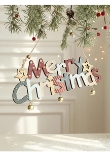 Detail of wooden Merry Christmas sign with metal bells hanging on a pine branch