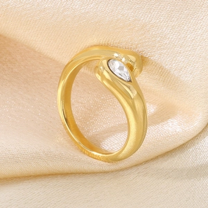 Detail of snake-shaped gold ring with pear-cut crystal on soft silk background
