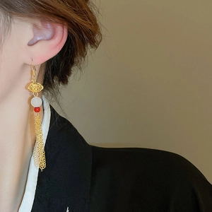 Close-up of cloud-shaped tassel earrings with white beads on a female model