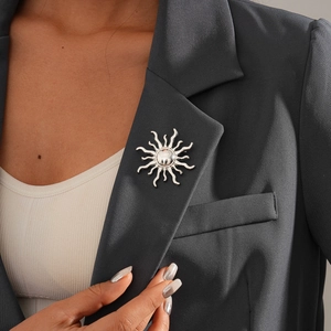 Macro shot of silver sunburst brooch with metallic rays pinned on a dark grey suit lapel