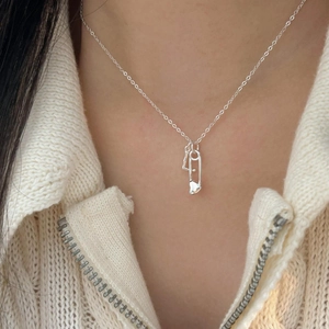 Close-up of S925 sterling silver safety pin necklace with heart charm on a model