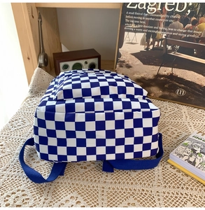 Detailed side view of blue and white checkered backpack on a rustic wooden table
