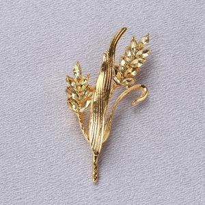 Macro shot of golden wheat brooch with sparkling yellow crystals on grey fabric