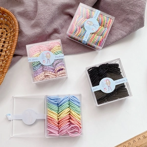 Close-up of four boxes featuring colorful candy-colored elastic hair ties for kids