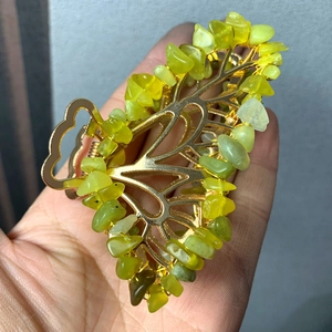 Detailed close-up of golden leaf hair claw with hand-wound green crystal stone chips