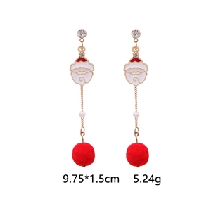 Detailed view of Christmas drop earrings with red pom-poms and gold chain tassels