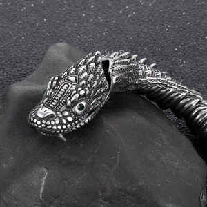 Detailed macro shot of vintage dragon head clasp with green gemstone eyes on steel bracelet