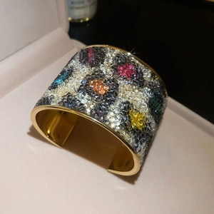 Detail of a gold cuff bracelet with multi-color leopard print crystals in a pink box