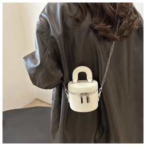Vue lifestyle d'un sac cylindrique blanc avec bandoulière chaîne et poignée