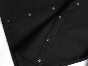 Detailed macro view of black wool blend jacket with high-quality metal snap buttons