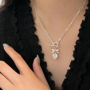 Detail of silver bow and heart zircon pendant with OT toggle clasp on double chain necklace