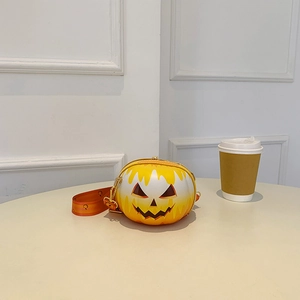 Detail of pumpkin-shaped crossbody bag with yellow-orange gradient and black smiley face