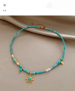 Gros plan d'un collier en turquoise et perles avec pendentif soleil doré sur soie