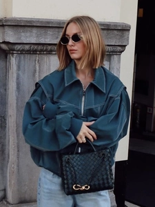 Women's oversized dark teal jacket with white topstitching and casual blue jeans