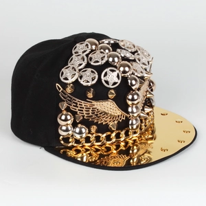 Détail de la casquette punk avec ailes dorées, rivets argentés et chaînes en métal