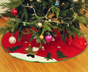 Detail of red Christmas tree skirt with plush snowman and tree appliques on wood floor