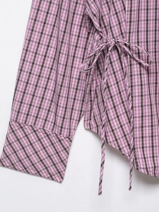 Détail de la chemise à carreaux rose avec lacets latéraux et coutures de poignets fines