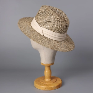 Detailed texture of straw fedora hat with elegant cream ribbon and bow on display