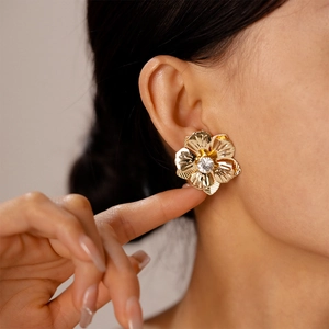 Gros plan d'une boucle d'oreille fleur dorée avec cristal porté par un mannequin