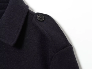 Détail de l'épaule d'un manteau en laine avec patte d'épaule et bouton noir élégant