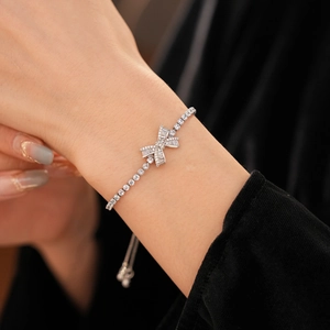 Close-up of zircon bow bracelet with adjustable slider chain on a black velvet background
