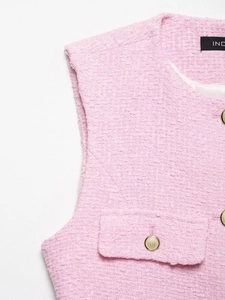 Gros plan sur le gilet en tweed rose montrant la texture et les boutons dorés
