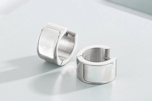 Detailed close-up of silver stainless steel hoop earrings with white shell inlay accents