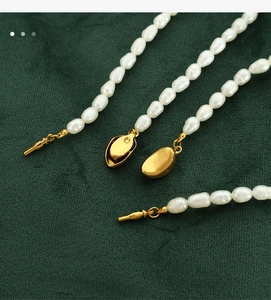 Macro shot of irregular freshwater pearl necklaces with gold pea clasp on green velvet