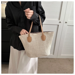 Detailed shot of beige straw tote bag with brown leather handles and durable woven texture