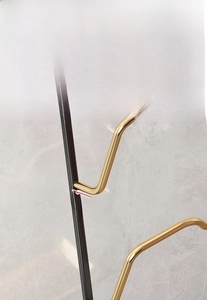 Detail of wall-mounted black and gold metal towel rack with water drainage gap